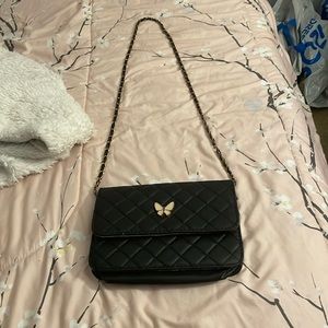 A black crossbody purse with a butterfly